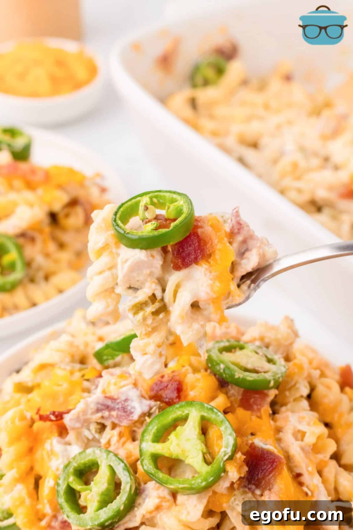 A bite of Chicken Jalapeno Popper Casserole on a fork, showing the creamy texture, chicken, bacon, and pasta.