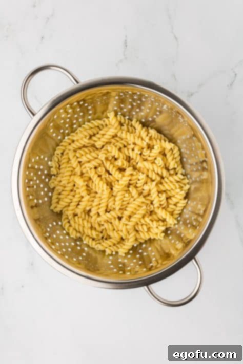 Boiled rotini in a strainer.