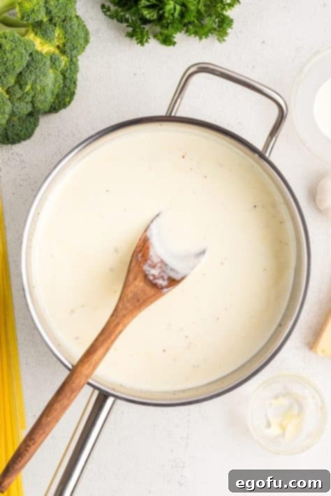 Heavy cream and Parmesan cheese blending into a creamy sauce in the skillet.
