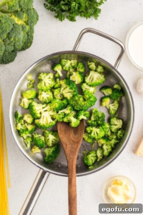 Broccoli cooking in a pan with water, pepper, and salt.