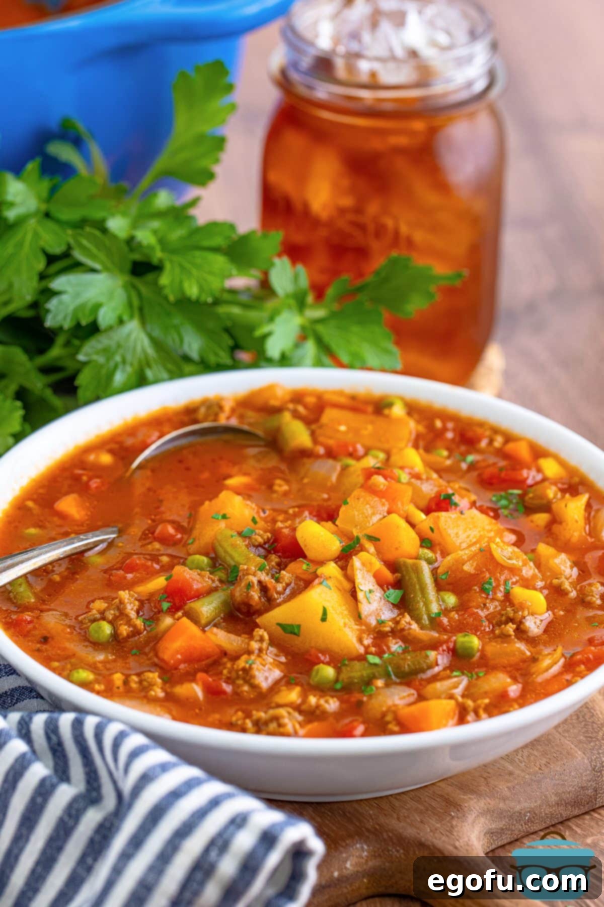 A large soup bowl of Hamburger Vegetable Soup with a soup spoon.