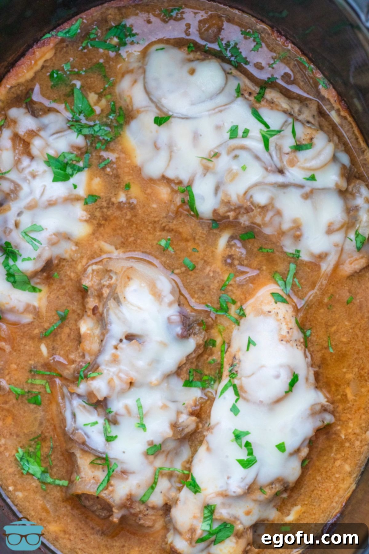 Looking down on Crock Pot French Onion Chicken covered in cheese.