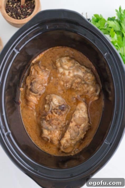 Cooked chicken in liquid in a slow cooker.