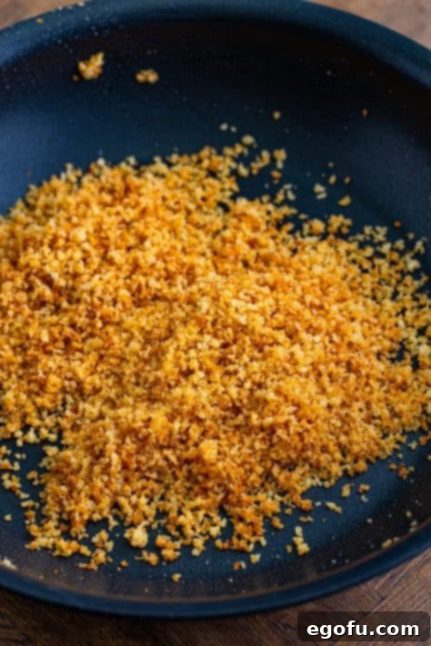 Panko breadcrumbs toasting in melted butter in a skillet.