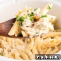 Creamy Slow Cooker Garlic Parmesan Chicken Pasta 8 A serving of Garlic Parmesan Chicken Pasta made in the Crock Pot on a wooden spoon.