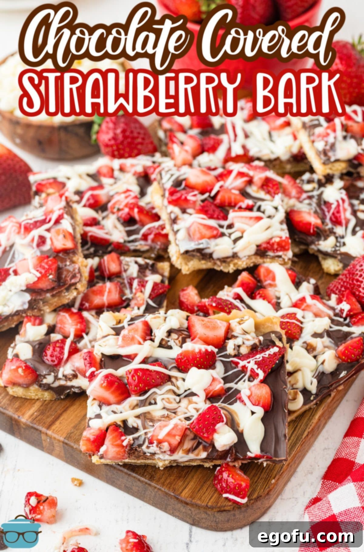 Decadent Strawberry Chocolate Bark 3 A cutting board with a couple pieces of Chocolate Covered Strawberry Bark, showcasing its layers.