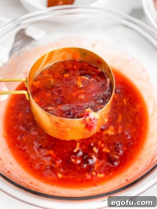 A measuring cup scooping sauce from a bowl.