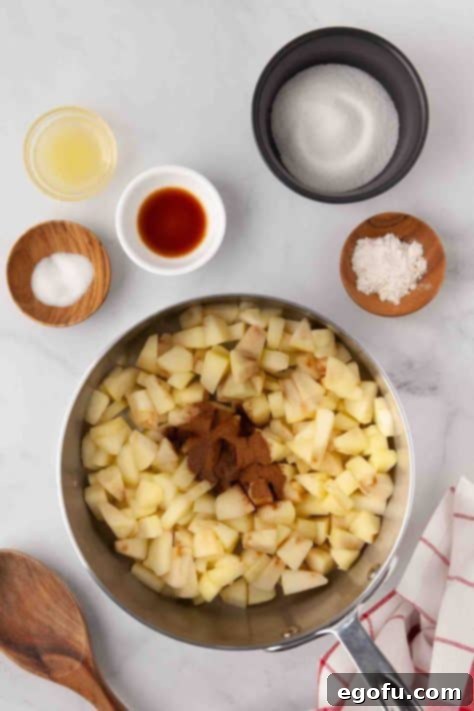 Apples with spices in a pan, beginning to cook.