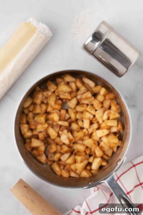 Cooked apple filling in a pan, now thickened and syrupy.