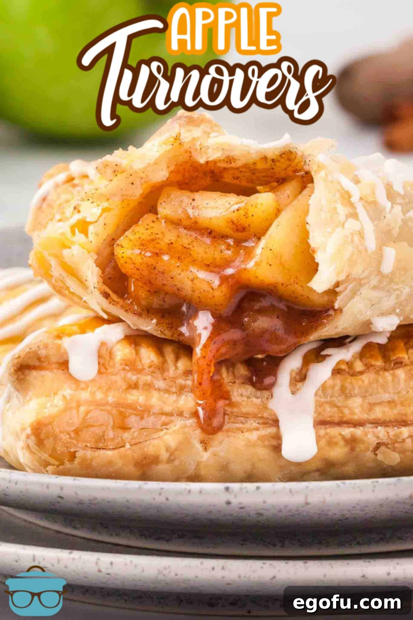 An Apple Turnover on a plate and another on top of it with a bite missing, showcasing the delicious filling.
