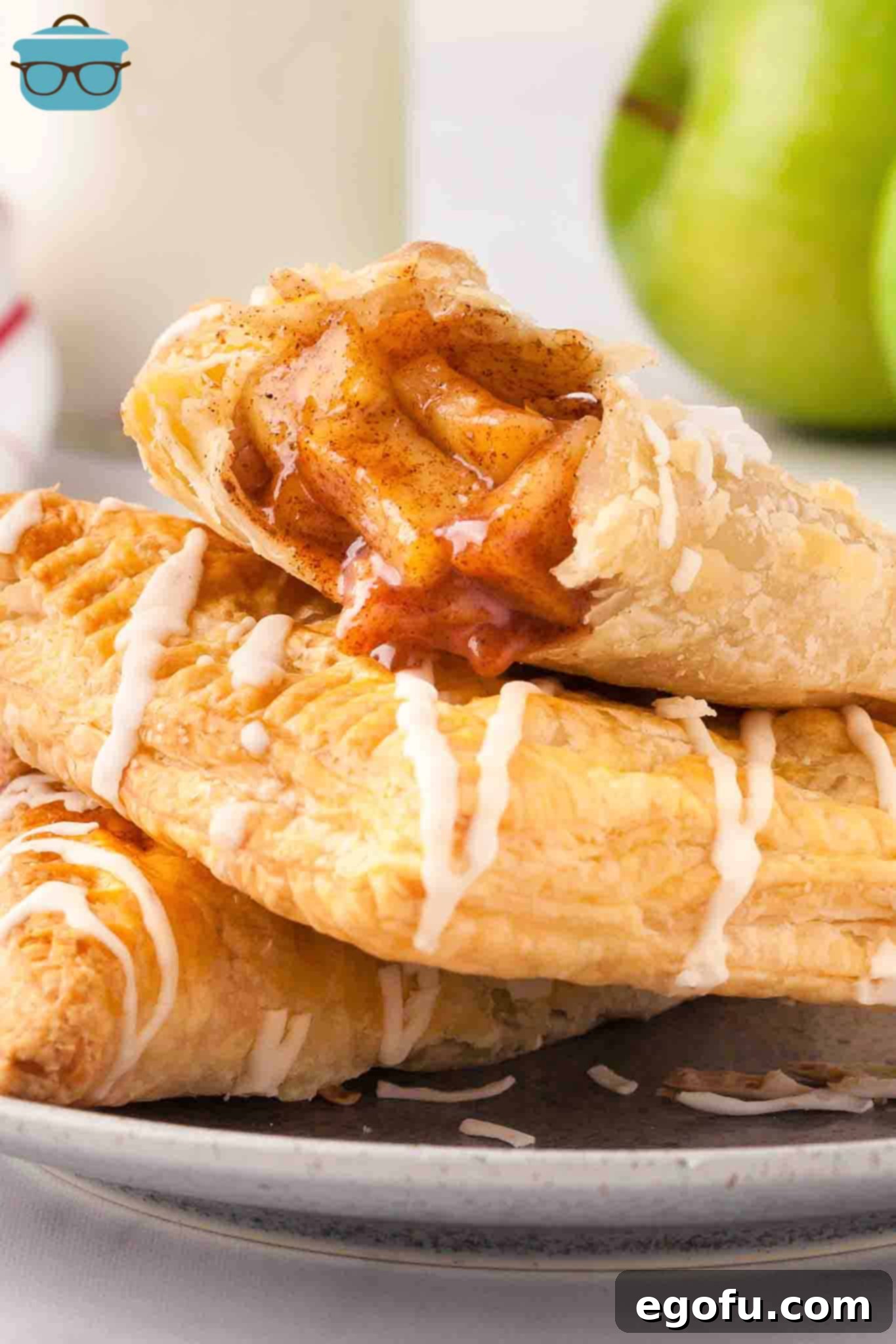 A small stack of Apple Turnovers on a plate, glistening with glaze.