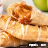 A small pile of Apple Turnovers, one with a bite missing, showing the flaky pastry.