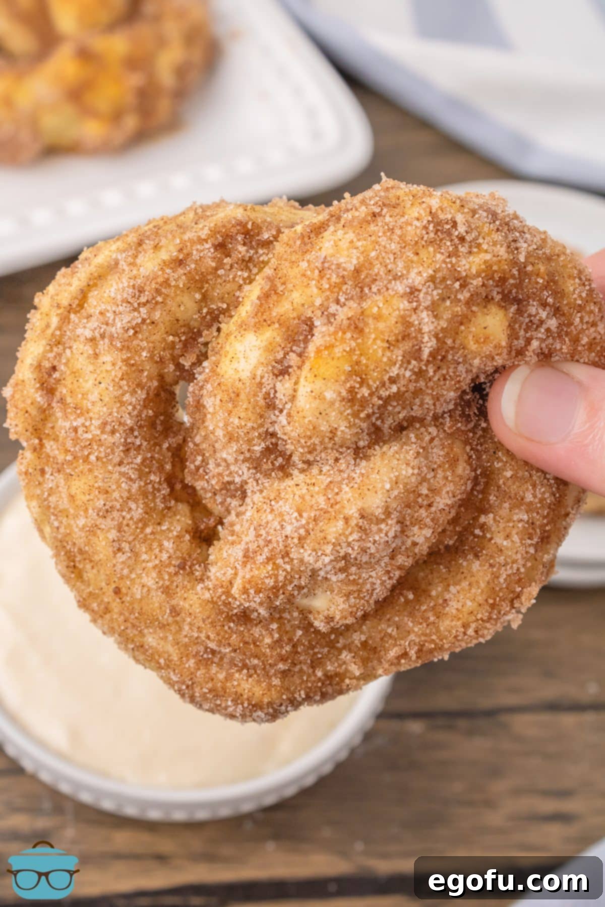 A hand holding a single homemade Cinnamon Sugar Pretzel, showcasing its golden-brown crust and sweet coating.