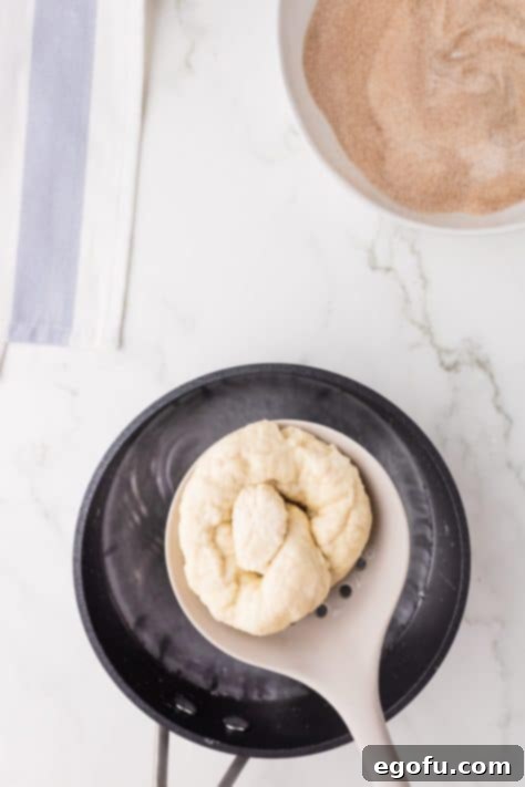 Pretzel being held over a hot baking soda bath.