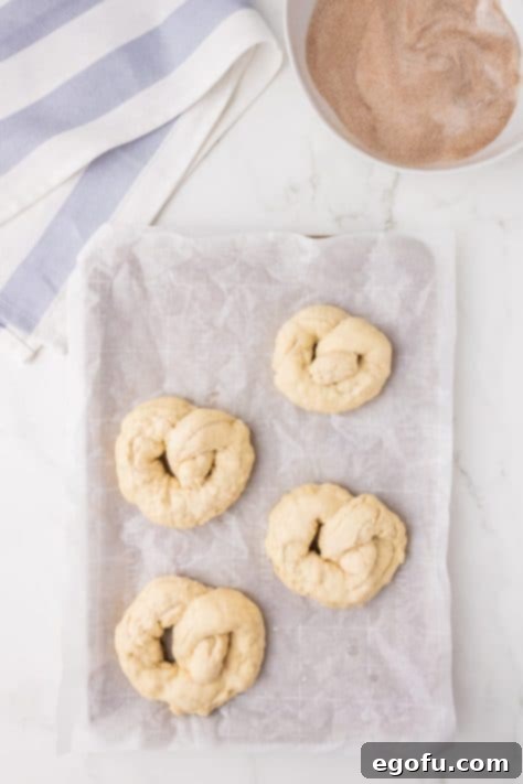 Boiled pretzels neatly arranged on a baking sheet, ready for the oven.