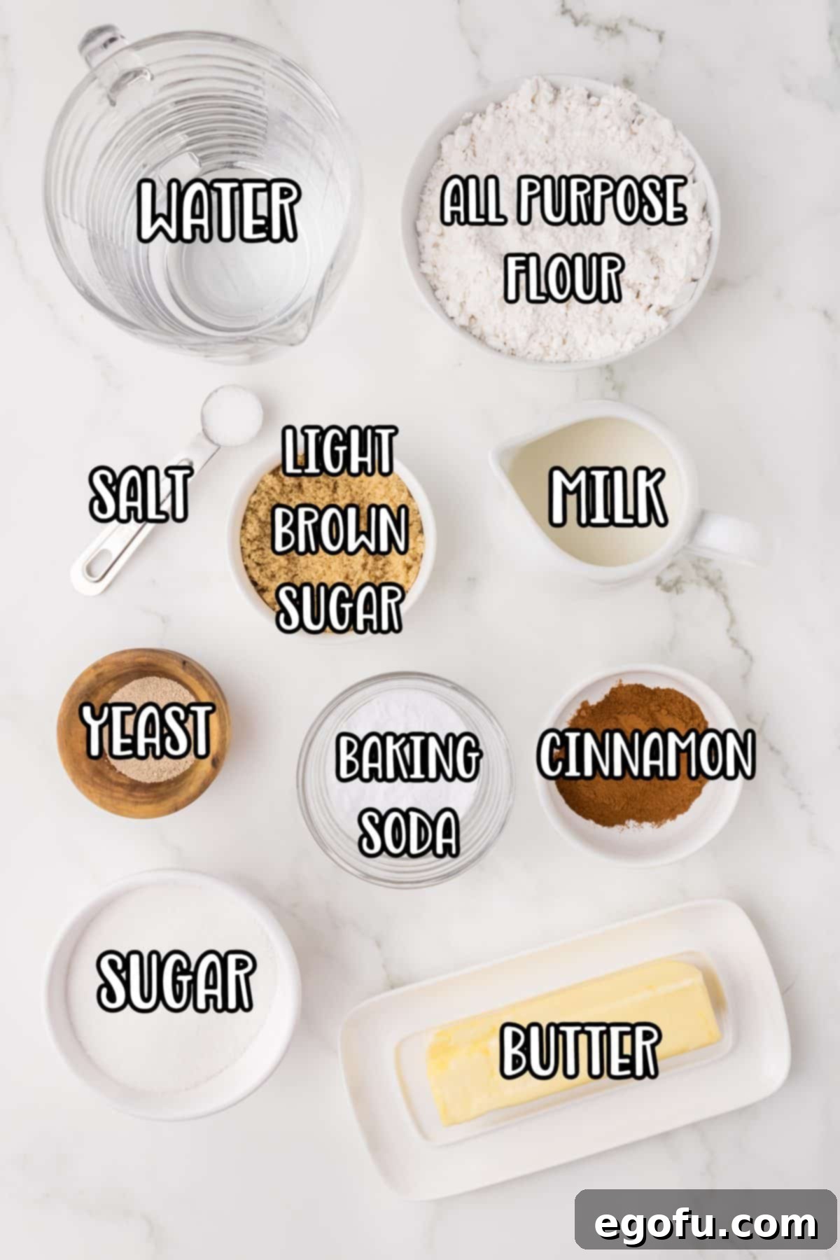 A collection of ingredients for cinnamon sugar pretzels, including yeast, milk, brown sugar, flour, salt, baking soda, water, butter, cinnamon, and granulated sugar.