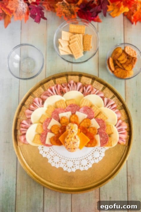 Crakcers, cheese, meats and cheeseball being shaped into a turkey.