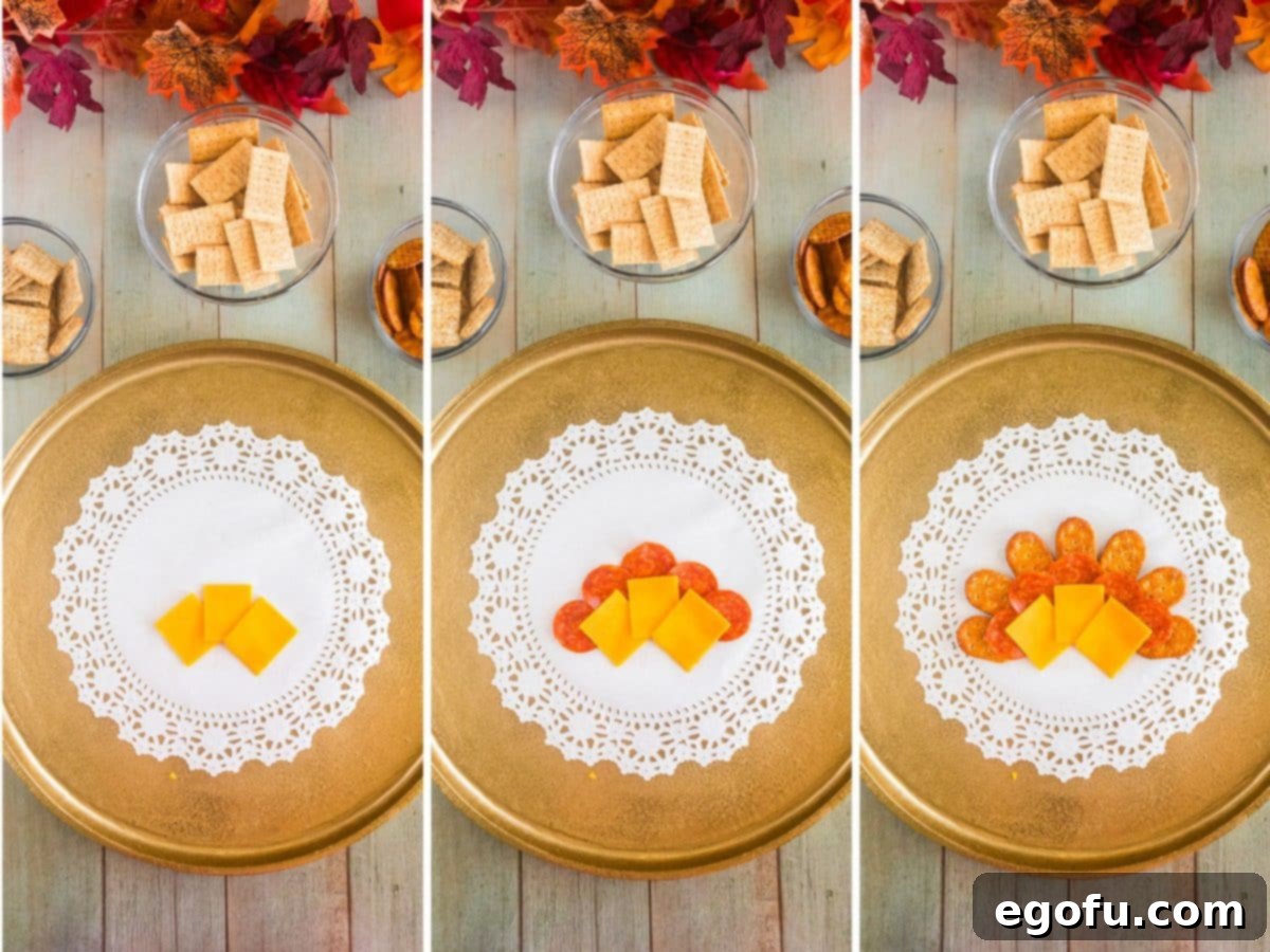 Initial layers of cheddar cheese, pepperoni, and pretzel crackers artfully arranged in semi-circles on a large platter, forming the first 'feathers' of the turkey.