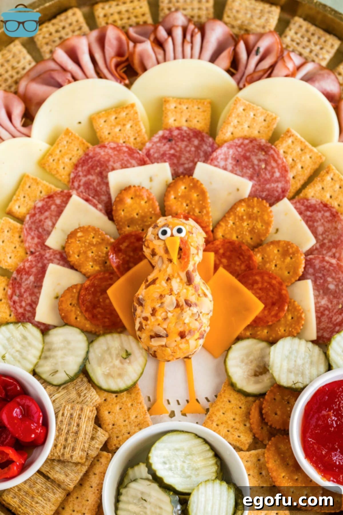 The finished Thanksgiving charcuterie board, a delightful turkey shape surrounded by small bowls of condiments and extra crackers, ready for serving.