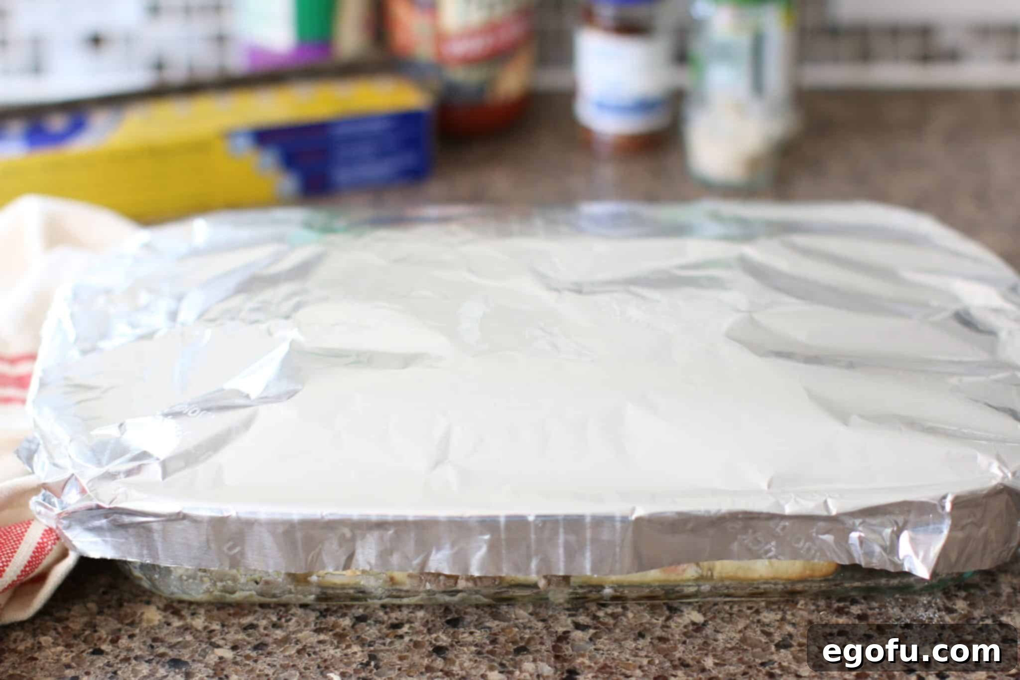 Baking dish covered with aluminum foil, prepared for the oven.