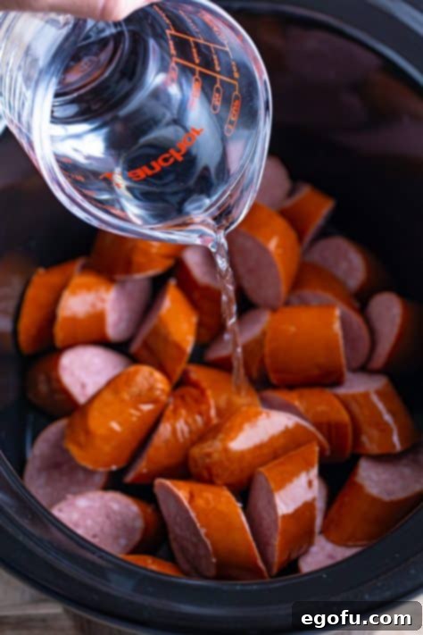 Water being added to kielbasa in a Slow Cooker.