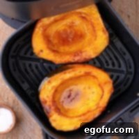 Perfectly Roasted Air Fryer Acorn Squash 9 Looking down on an Air Fryer basket with roasted Acorn Squash halves, perfectly golden and tender.