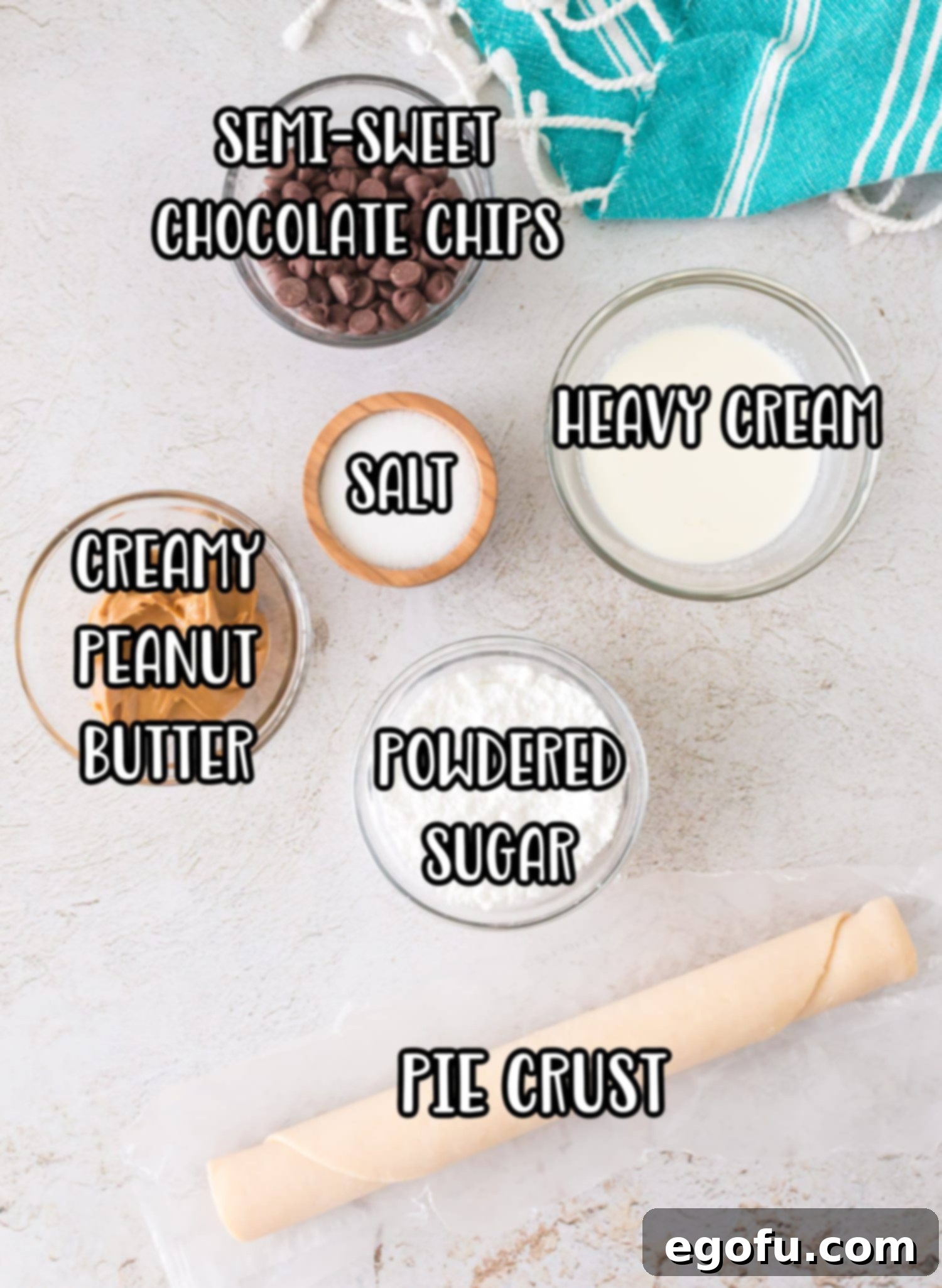 An array of ingredients laid out on a surface, including a pie crust, jar of peanut butter, bowl of powdered sugar, heavy cream, semi-sweet chocolate chips, salt, and sprinkles, ready for making Buckeye Mini Pies.