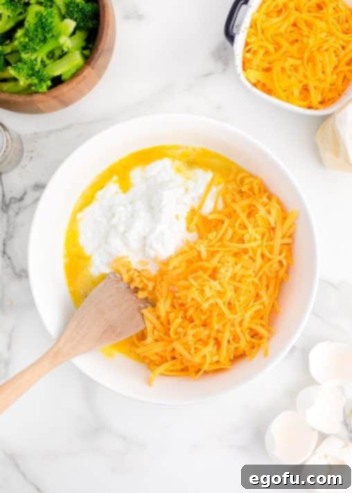 Homestyle Broccoli Cheddar Cornbread 12 Cottage cheese and shredded cheese being added to beaten eggs.
