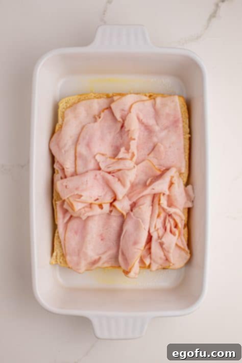 Zesty BBQ Chicken Sliders 10 Sliced chicken on top of Hawaiian roll bottoms in a dish.