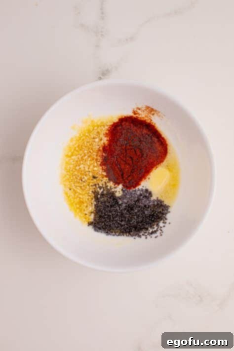 Zesty BBQ Chicken Sliders 15 A mixing bowl with melted butter, maple syrup, dried onion, paprika and poppy seeds.