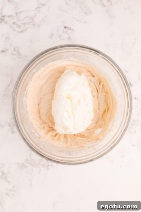 Cool Whip being added to a dessert dip.