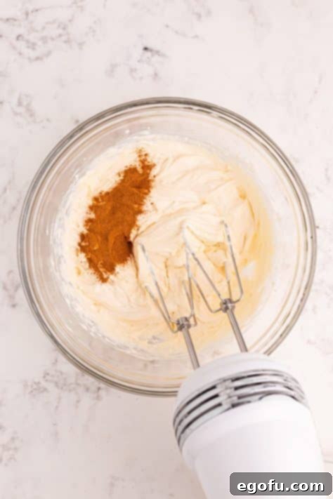 A bowl with apple pie spice, softened cream cheese, sweetened condensed milk and vanilla extract.