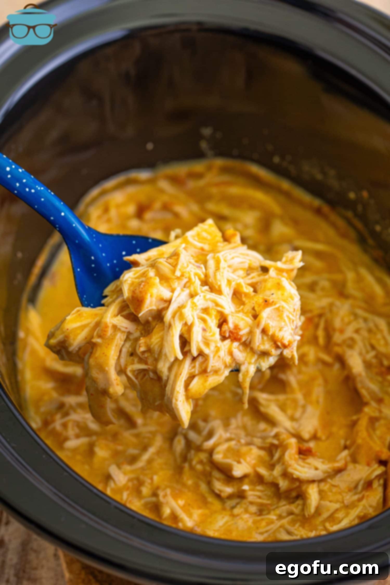 Date Night Slow Cooker Chicken and Gravy 8 A blue spoon holding a scoop of Crock Pot Chicken and Gravy for Two over the rest of the pot.