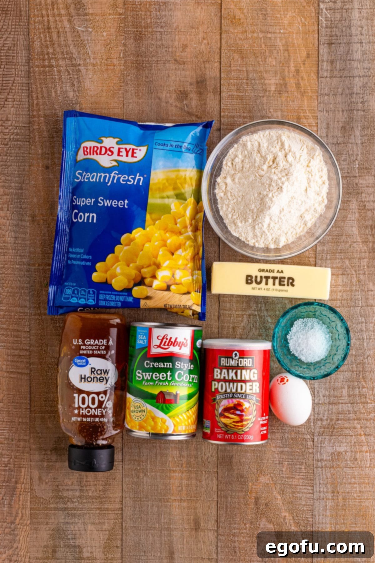 Sweet Corn Fritters 4 An array of fresh ingredients: frozen corn, baking powder, all-purpose flour, butter, cream-style corn, an egg, salt, and honey, neatly arranged for Corn Fritter preparation.