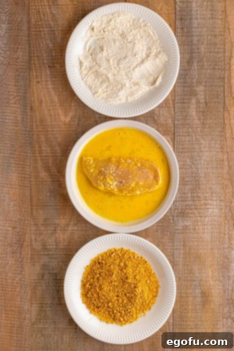 California Stuffed Chicken 16 Chicken in the egg mixture on a plate.