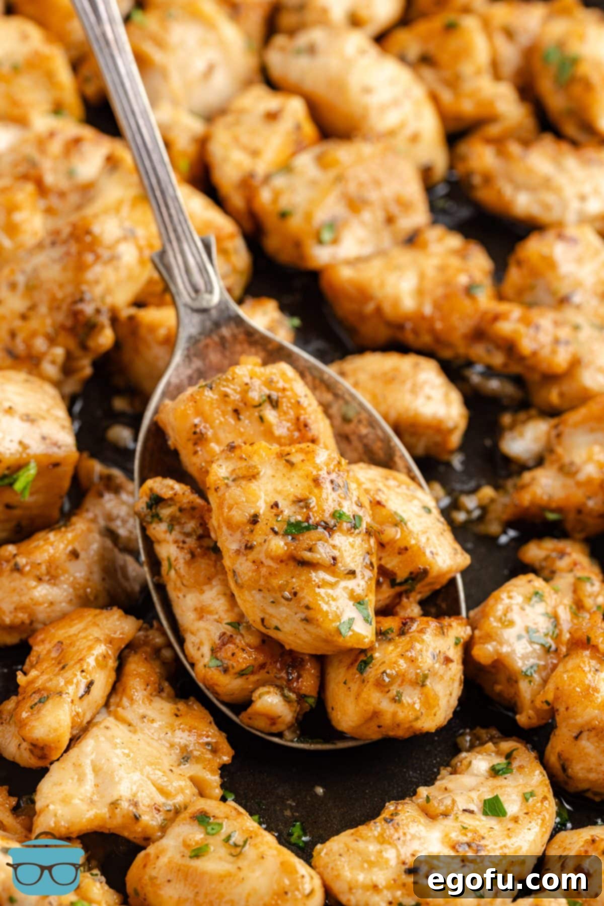 A spoon holding a scoop of Garlic Butter Chicken Bites above the rest.