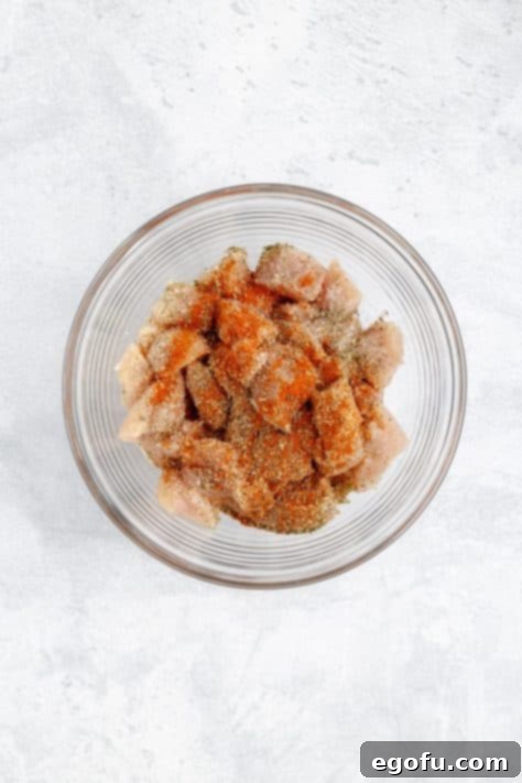 A bowl with chicken breast pieces with Italian seasoning, smoked paprika, onion powder, salt, and pepper.