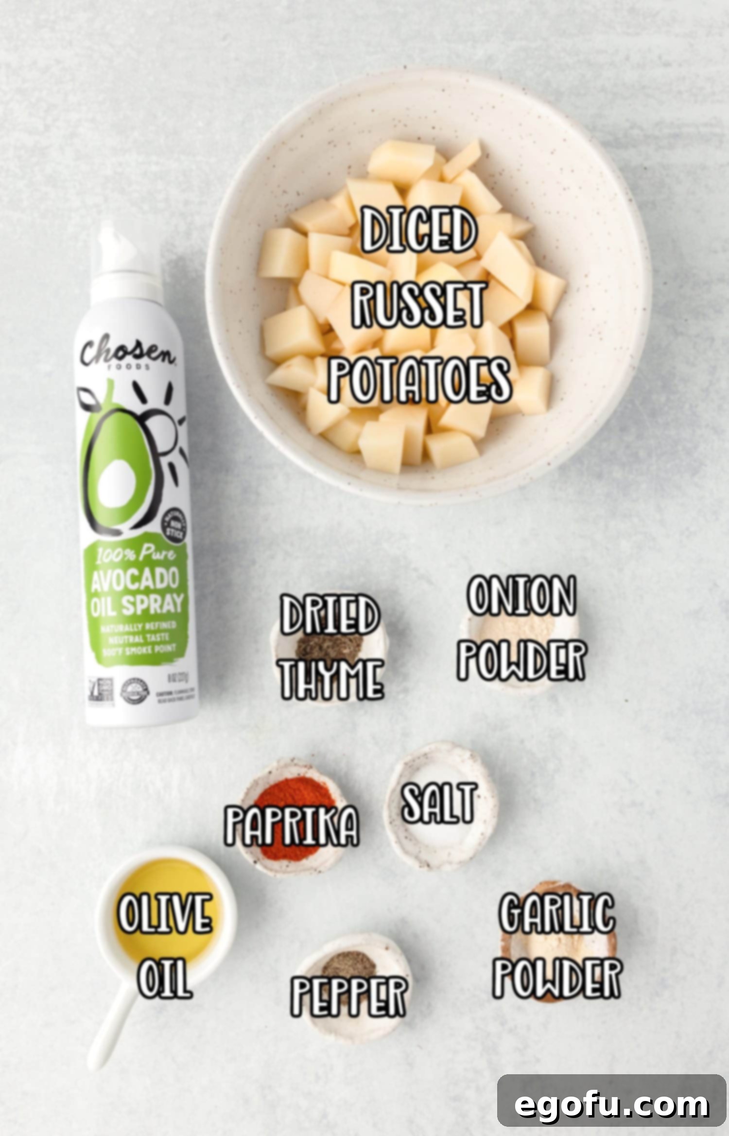 Crispy Air Fryer Breakfast Potatoes 4 A flat lay of all the ingredients: cooking spray, cubed Russet potatoes, paprika, garlic powder, onion powder, salt, olive oil, thyme, and black pepper, ready for preparation.