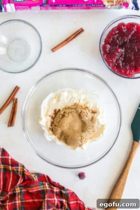 A bowl with cream cheese, ground cinnamon and brown sugar.