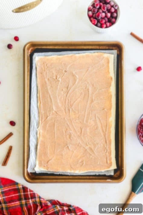 Puff pastry spread out with cream cheese mixture on it.