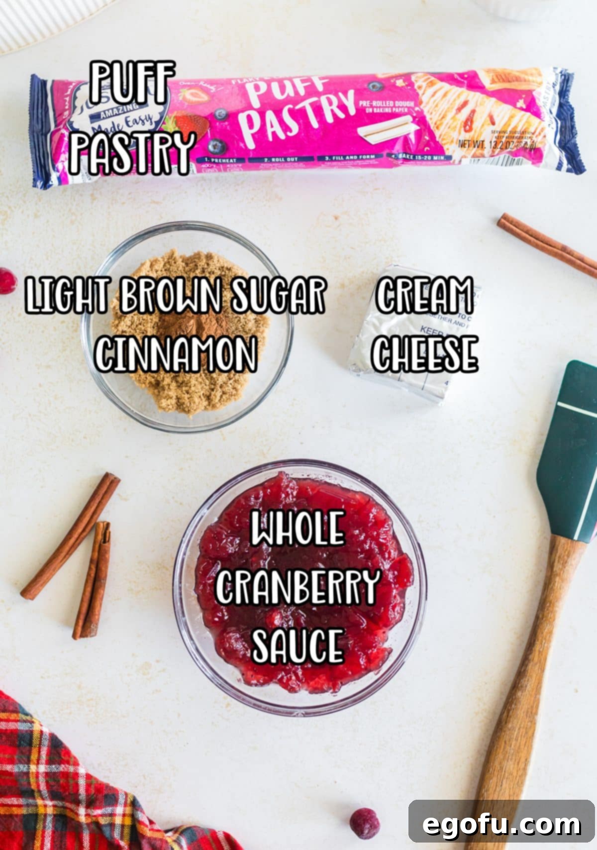 A collection of ingredients for Cranberry Pinwheels: puff pastry, whole cranberry sauce, light brown sugar, ground cinnamon, and cream cheese.