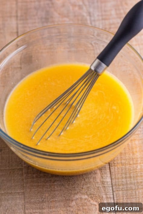 Chicken stock and gravy being whisked together in a bowl.