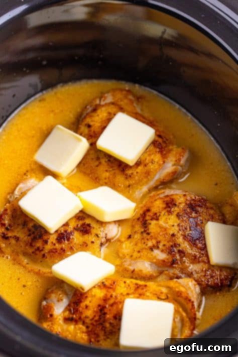 Butter slices over chicken in a Crockpot.