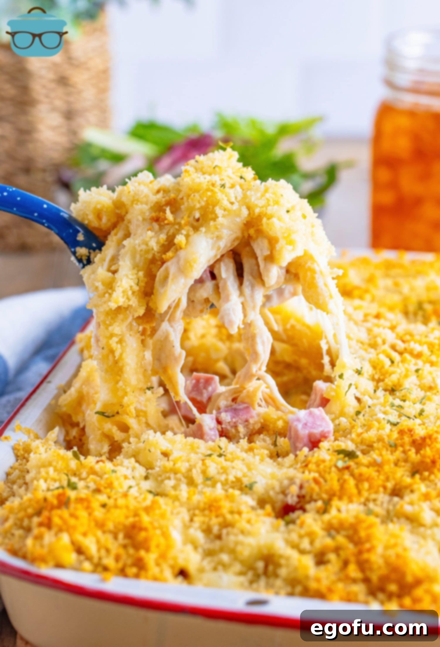 A large scoop of Malibu Chicken Casserole being removed from a casserole dish, showcasing its creamy texture and golden-brown topping.