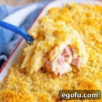 A close-up of the Malibu Chicken Casserole in a dish, with a scoop being taken, highlighting the golden topping and rich interior.