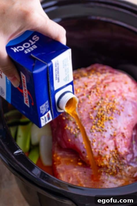 Set-It-and-Forget-It Corned Beef 13 Beef stock being poured into a Slow Cooker over the brisket.