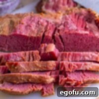 Set-It-and-Forget-It Corned Beef 10 A close-up view of beautifully sliced slow cooker corned beef on a cutting board, highlighting its tender texture.