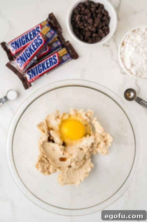 A bowl with butter, granulated sugar, vanilla extract, egg, and light brown sugar.