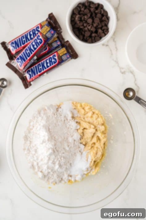 Flour, salt, and baking powder being added to wet cookie dough.