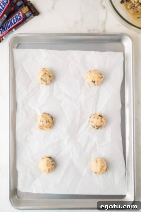 Six balls of Snicker Cookie dough on a baking sheet.